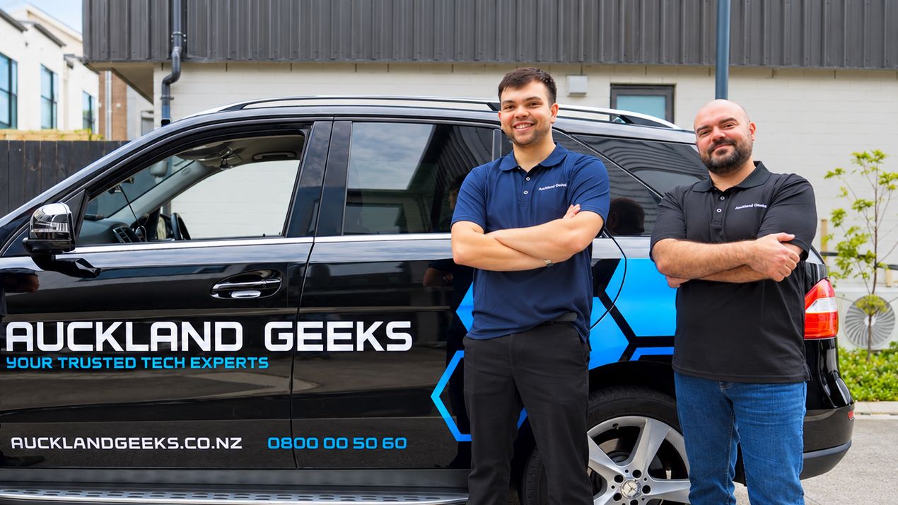 Two Auckland Geeks technicians beside their branded car
